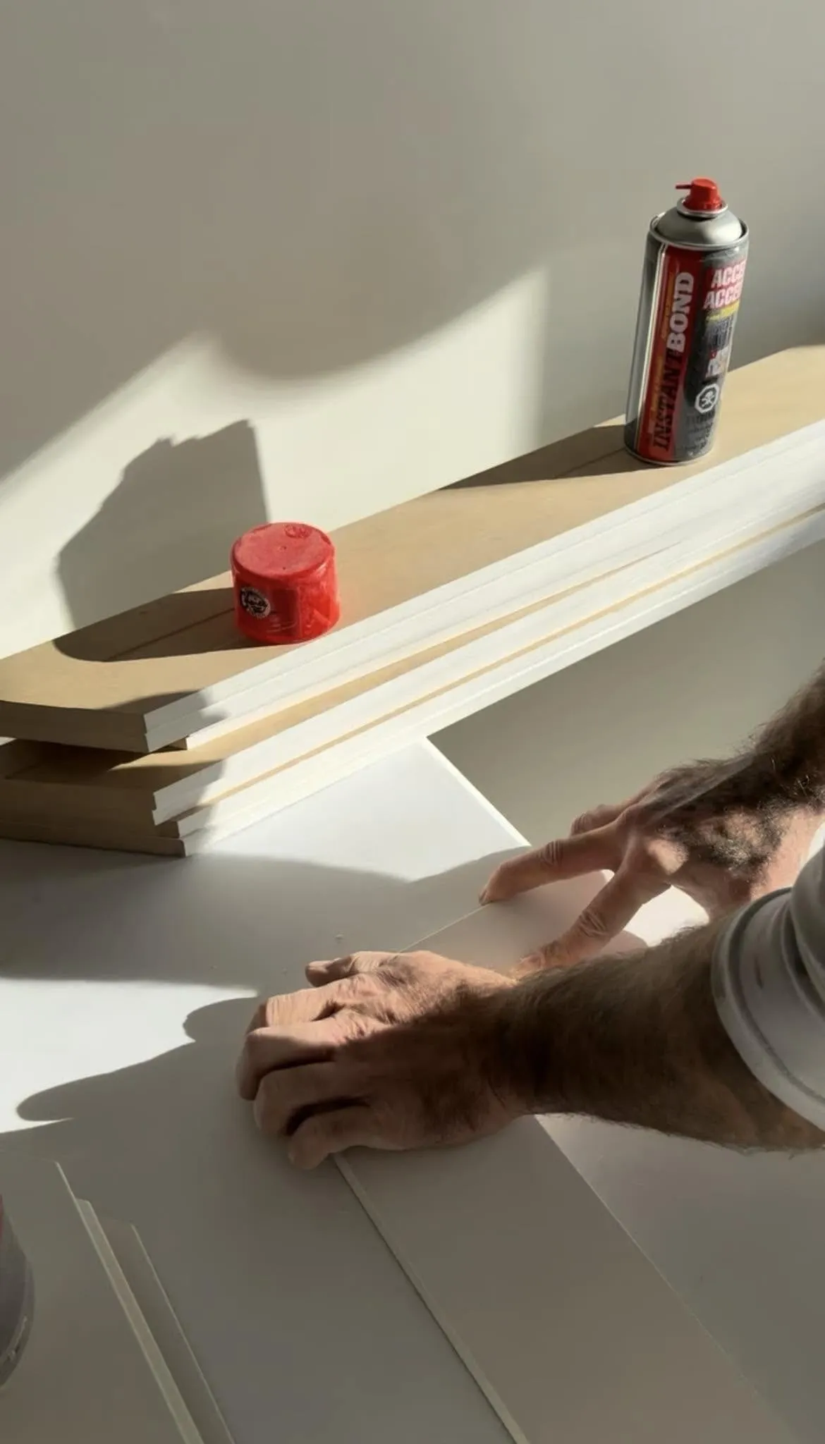 Hands squaring a length of primed casing on a bench, saw and caulk behind
