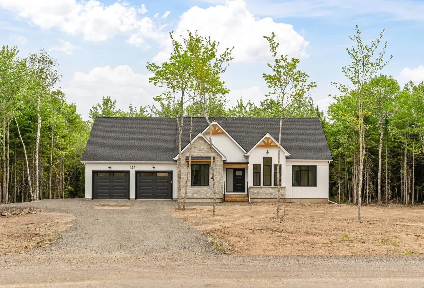 The finished house from the drive, grey roof and white board siding among birches