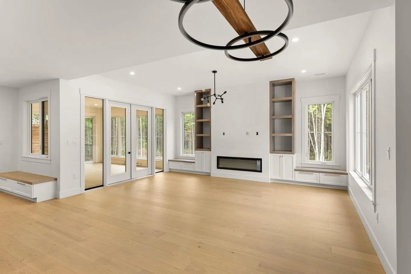 A finished living room: built-in shelving, a linear fireplace, oak floor and painted walls