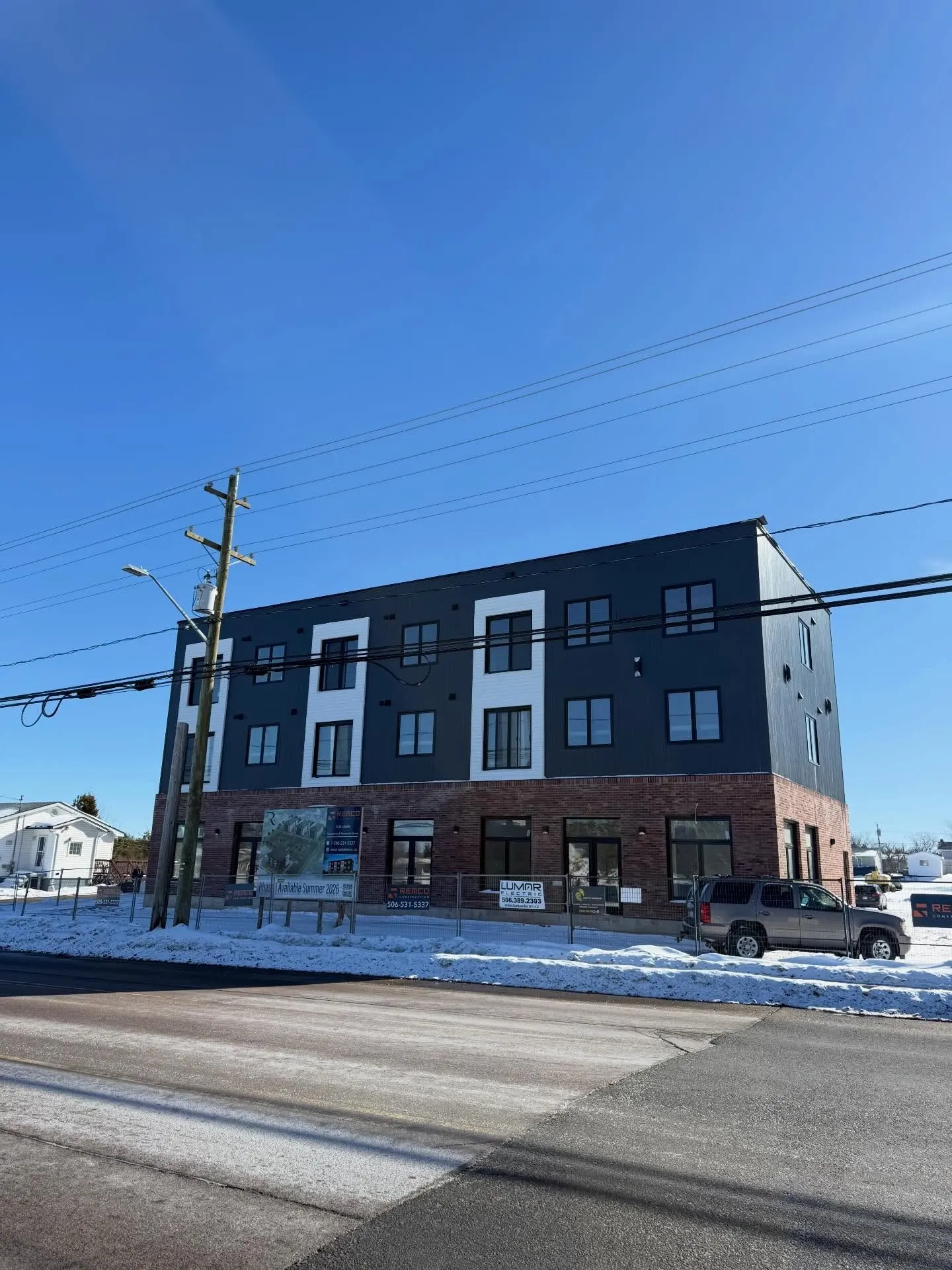 A finished four-storey residential building in dark siding and brick on a winter afternoon
