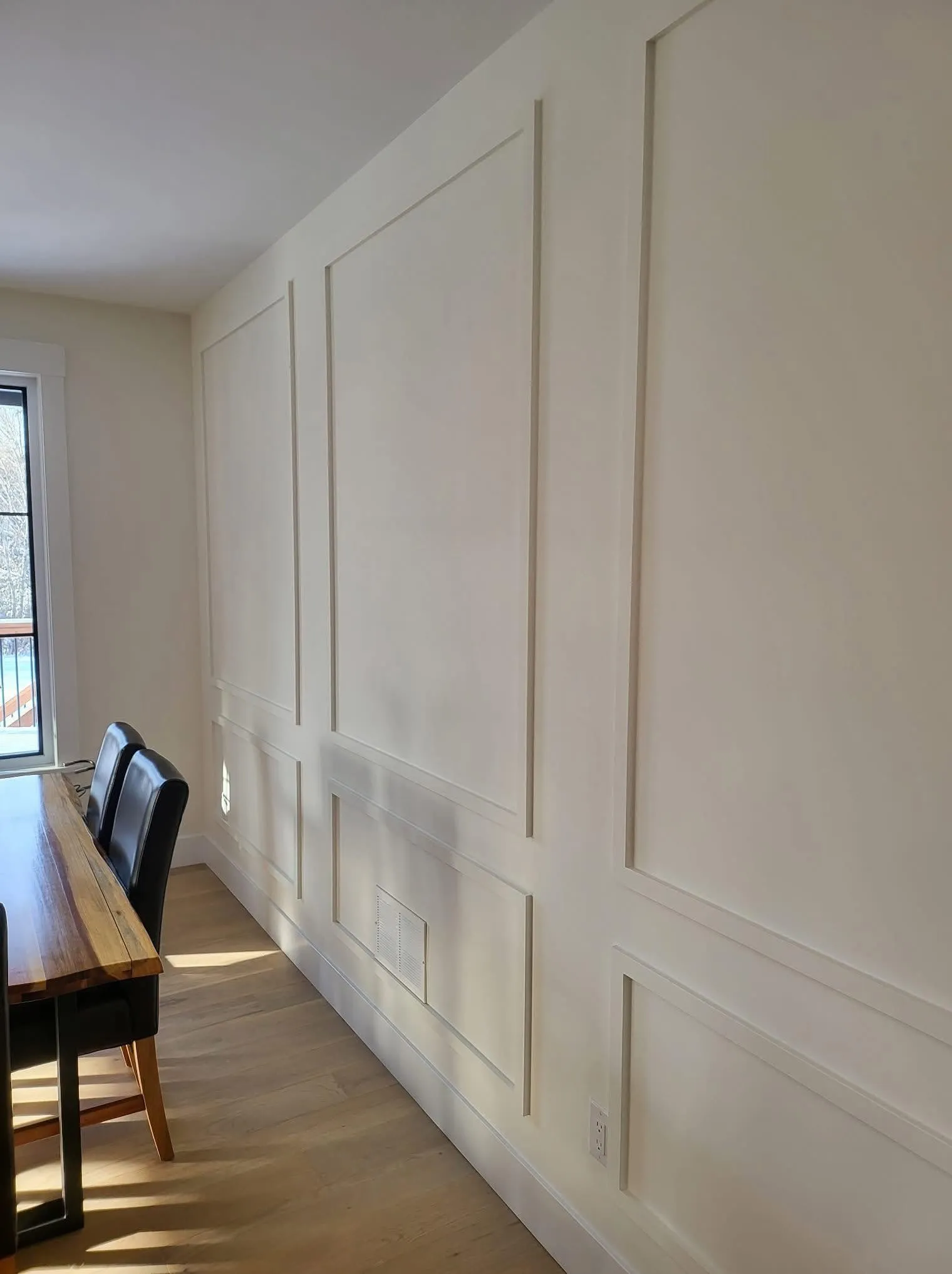 A panelled feature wall installed and painted, dining table beside it