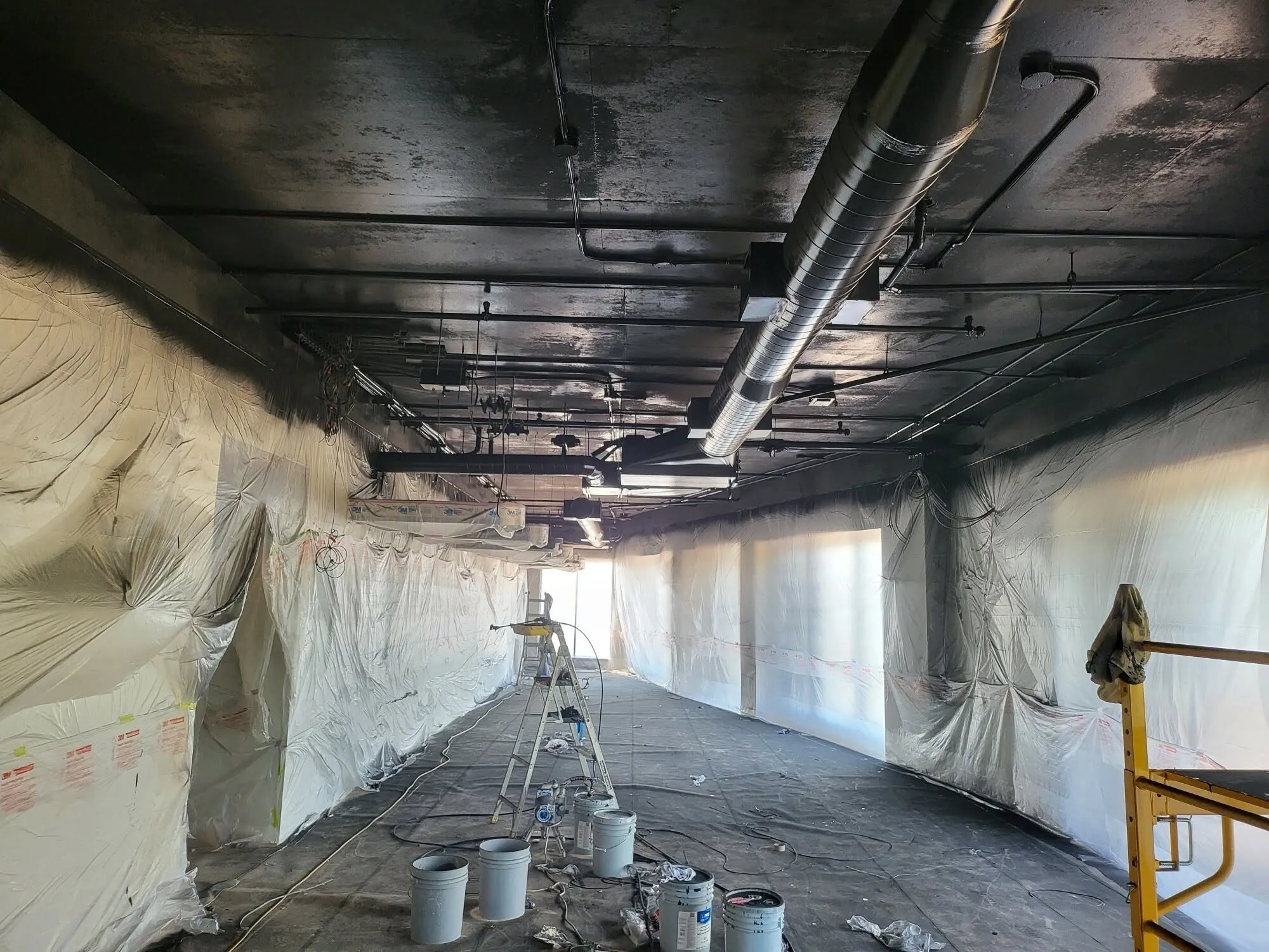 The ceiling sprayed out black, walls masked, paint and a ladder on the slab